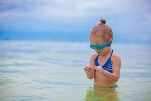 Little girl with glasses for swimming swims and dives in the sea photo