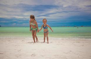 Two little sisters in nice swimsuits out of the sea at tropical exotic beach photo