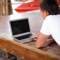 Back view of young man with laptop outdoor on vacation photo