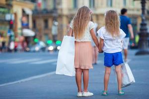 Adorable fashion little girls with purchases outdoors in European city photo