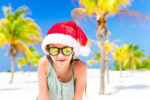 Portrait of little girl in Santa hat during Christmas beach vacation photo