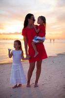 silueta de mamá e hijas al atardecer en la playa de boracay foto