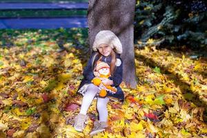 Little beautiful girl on the autumn meadow in a sunny fall day photo