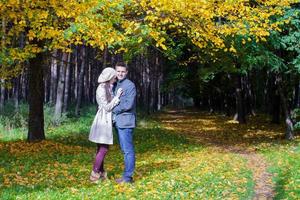 Young couple in love on the big autumn meadow under large maple tree at sunny fall day photo