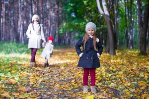 Young mother and her adorable daughter walking in yellow autumn forest on a warm sunny day photo