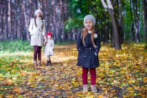 en primer plano hay una hermosa y dulce niña detrás de su madre y su hermana en el parque de otoño foto