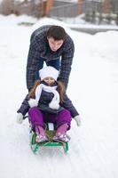 Young father with his baby daughter in a sleigh ride and enjoy sunny winter day photo