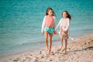 Little happy funny girls have a lot of fun at tropical beach playing together. photo