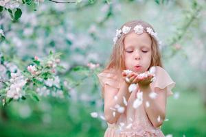 Adorable little girl enjoying spring day in apple blooming garden photo
