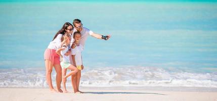 Man taking a photo of his family on the beach