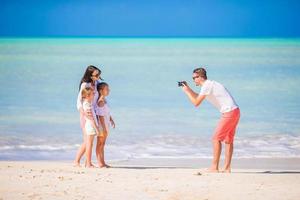 Man taking a photo of his family on the beach