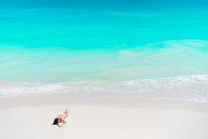 Young beautiful girl on the beach at shallow tropical water top view photo