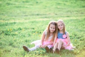Adorable little girls on spring day outdoors sitting on the grass photo