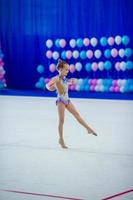 Beautiful little active gymnast girl with her performance on the carpet photo