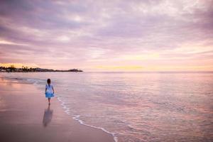 Sihouette of little girl dancing on the beach at sunset. photo