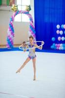 Beautiful little active gymnast girl with her performance on the carpet photo