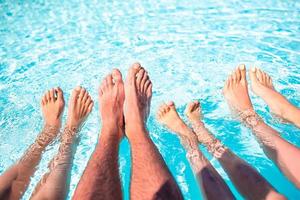 Cerca de las piernas de cuatro personas al lado de la piscina foto