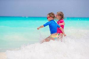 Kids having fun at tropical beach playing together at shallow water photo