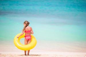 Little girl with yellow inflatable rubber circle going to swim in the ocean