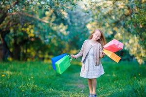 adorable niña con bolsas de compras al aire libre en el jardín de manzanas foto