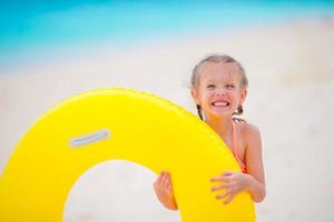 Little girl with inflatable rubber circle on white beach at caribbean vacation photo