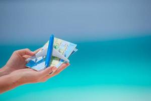 Small white miniature of an airplane and map on background of turquoise sea photo