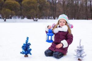 Adorable little girl holding Christmas lantern outdoors on beautiful winter snow day photo