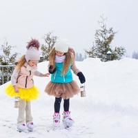 Adorable little girls skating on ice rink outdoors photo