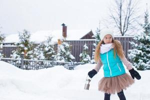 adorable niña sosteniendo linterna de navidad al aire libre en un hermoso día de nieve de invierno foto