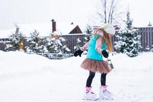 adorable niña patinando en un día nevado de invierno al aire libre foto
