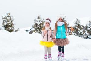 Little happy girls skating outdoors in winter snow day photo