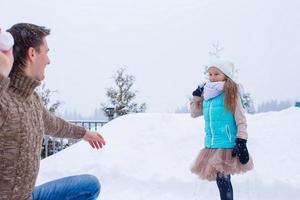 Happy father and little girl playing snowballs in winter snowy day photo