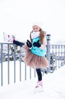 Adorable little girl skating on ice rink outdoors in winter snow day photo