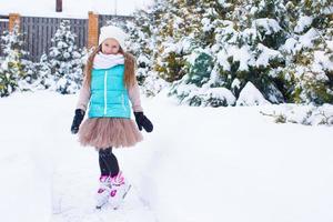 Adorable little girl skating in winter snow day outdoors photo