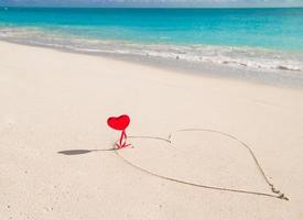 Heart painted in white sand on a tropical beach photo