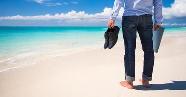 Young man with laptop during tropical beach vacation photo