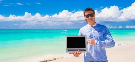joven con laptop durante las vacaciones en la playa foto