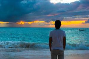 joven disfrutando de la puesta de sol durante las vacaciones en la playa foto