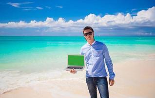 Young man with laptop during beach vacation photo