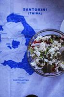 Greek salad on the table with map of Santorini, Greece photo