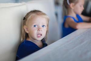 Adorable little girl having breakfast at restaurant photo