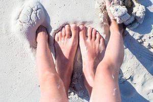 primer plano de los pies de la madre y el niño en la playa de arena blanca foto