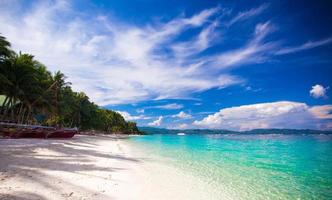 Tropical beach with white sand and a small boat photo