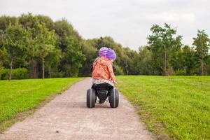 Back view of adorable little girls ride a motorbike outdoor photo