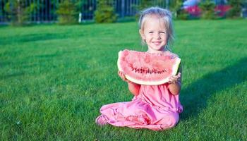 Little adorable funny girl with a piece of watermelon in hands photo