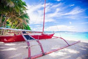 Filipino red boat on the white sand beach in Boracay island, Philippines photo