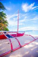 Filipino red boat on the white sand beach in Boracay island, Philippines photo