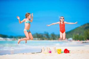 Little girls playing with beach toys during tropical vacation photo
