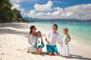 familia joven y dos niños con palabra amor en vacaciones tropicales foto