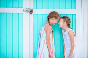 Adorable little girls on summer vacation background traditional colorful caribbean house photo